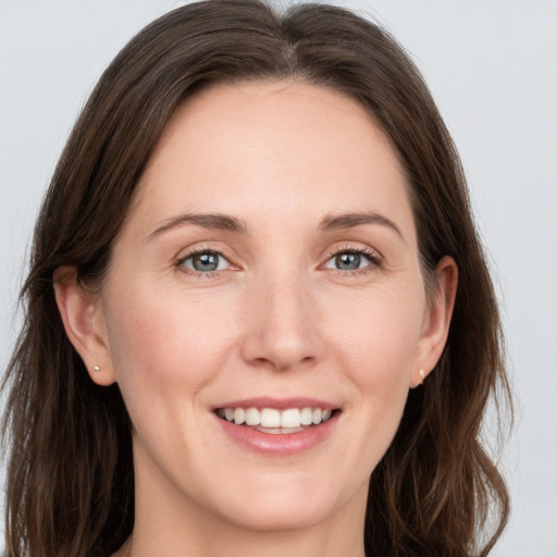 Joyful white young-adult female with long  brown hair and grey eyes