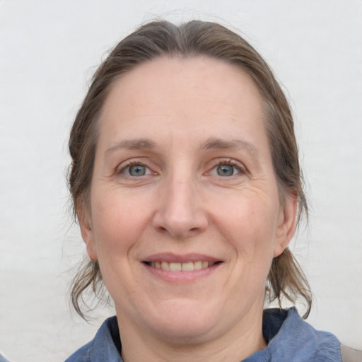 Joyful white adult female with medium  brown hair and blue eyes