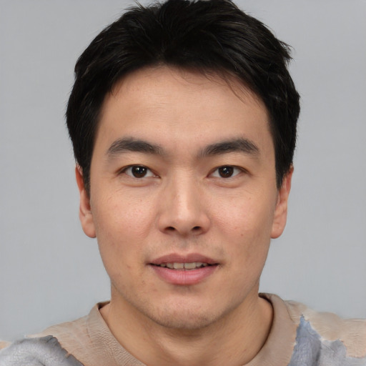 Joyful asian young-adult male with short  black hair and brown eyes