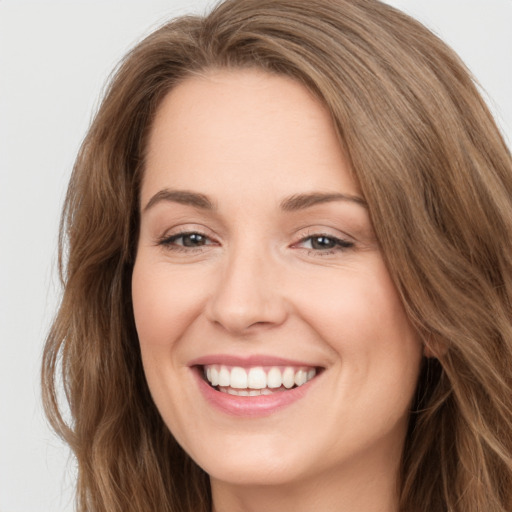 Joyful white young-adult female with long  brown hair and brown eyes