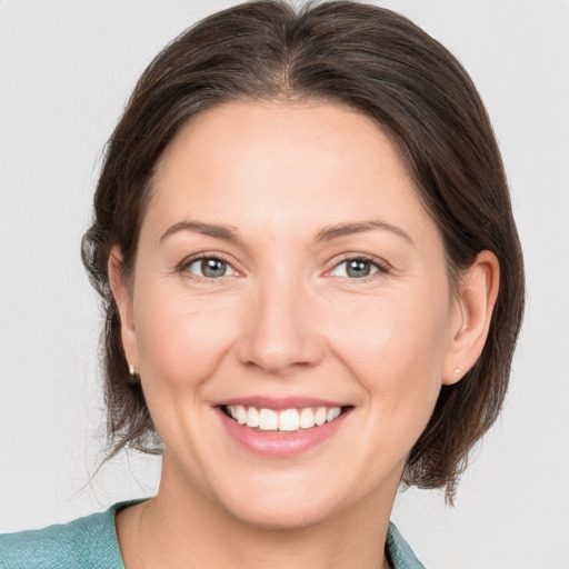 Joyful white young-adult female with medium  brown hair and grey eyes