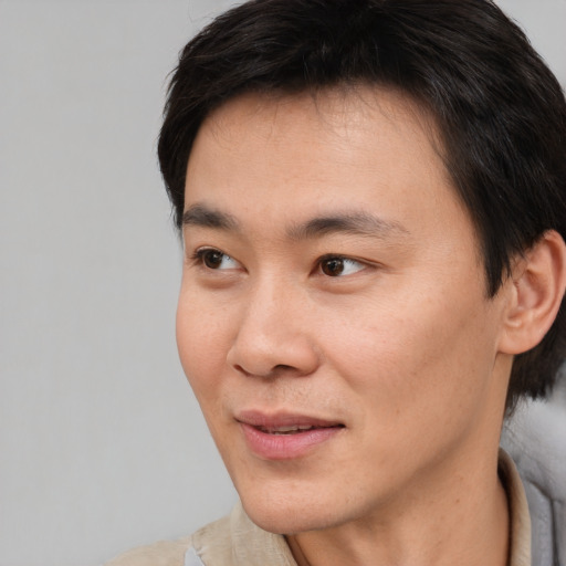 Joyful asian young-adult male with short  brown hair and brown eyes