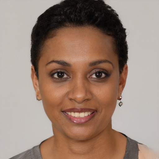 Joyful black young-adult female with short  black hair and brown eyes