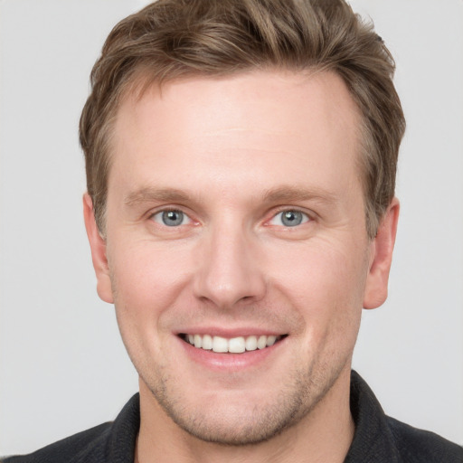 Joyful white young-adult male with short  brown hair and grey eyes