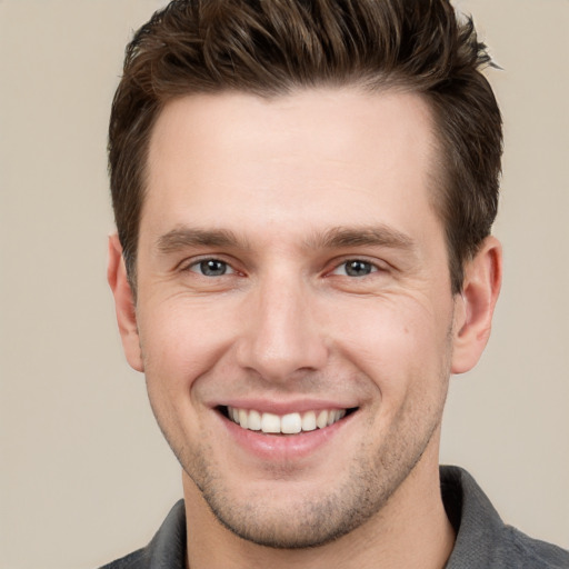 Joyful white young-adult male with short  brown hair and grey eyes