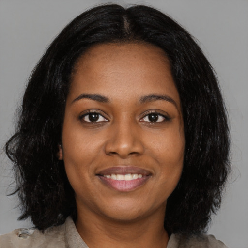 Joyful black young-adult female with long  black hair and brown eyes