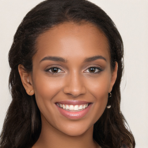 Joyful black young-adult female with long  brown hair and brown eyes