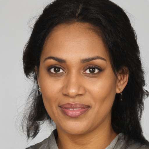 Joyful black adult female with long  brown hair and brown eyes