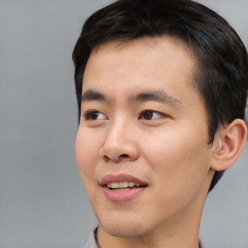Joyful asian young-adult male with short  brown hair and brown eyes