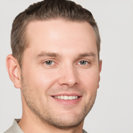 Joyful white young-adult male with short  brown hair and grey eyes