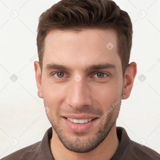 Joyful white young-adult male with short  brown hair and grey eyes