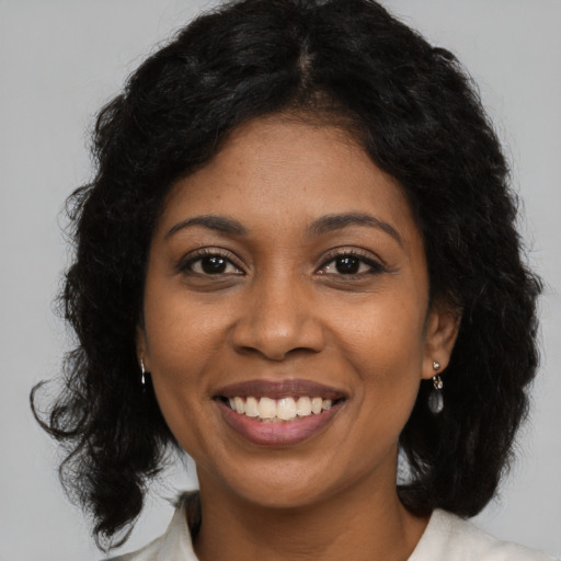 Joyful black young-adult female with long  black hair and brown eyes