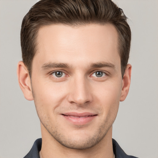 Joyful white young-adult male with short  brown hair and grey eyes