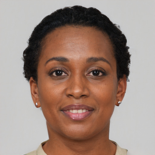 Joyful black young-adult female with short  black hair and brown eyes