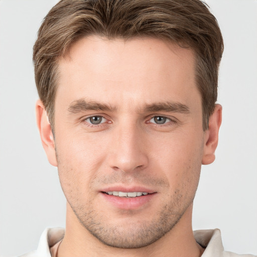 Joyful white young-adult male with short  brown hair and grey eyes