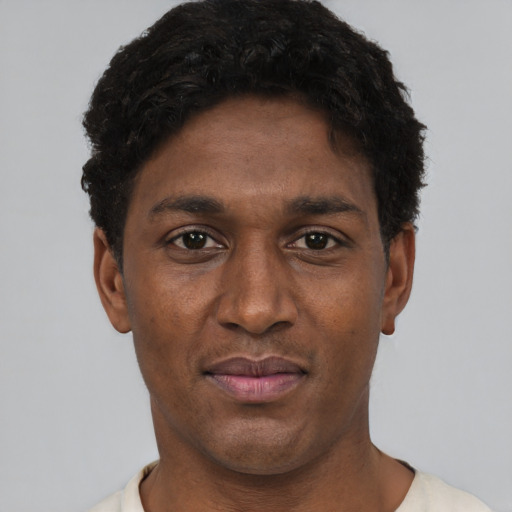 Joyful black young-adult male with short  black hair and brown eyes
