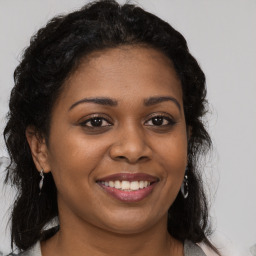 Joyful black young-adult female with long  brown hair and brown eyes