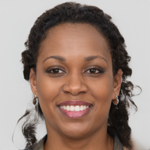 Joyful black young-adult female with long  brown hair and brown eyes