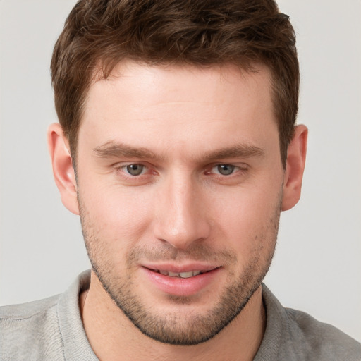 Joyful white young-adult male with short  brown hair and grey eyes