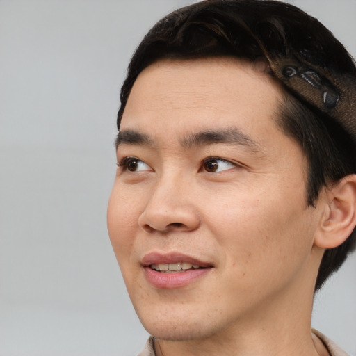 Joyful asian young-adult male with short  brown hair and brown eyes