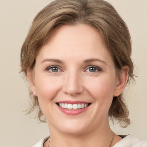 Joyful white young-adult female with medium  brown hair and grey eyes