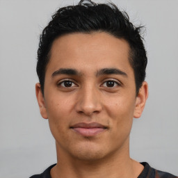 Joyful latino young-adult male with short  black hair and brown eyes