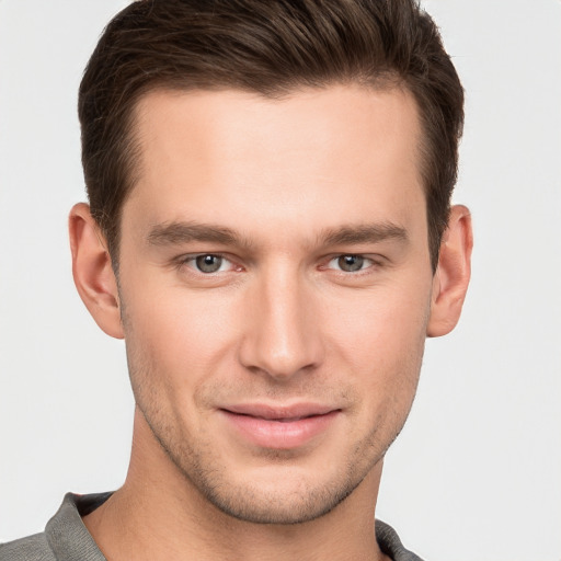 Joyful white young-adult male with short  brown hair and grey eyes