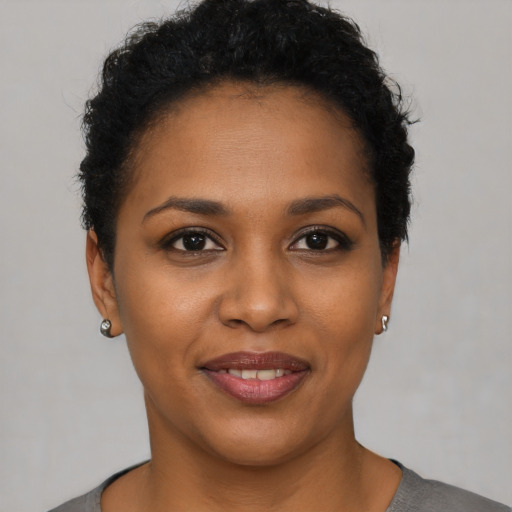Joyful black young-adult female with short  black hair and brown eyes