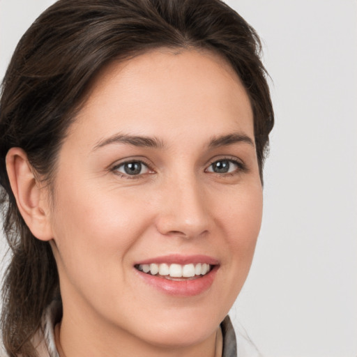 Joyful white young-adult female with medium  brown hair and grey eyes