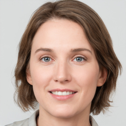 Joyful white young-adult female with medium  brown hair and grey eyes