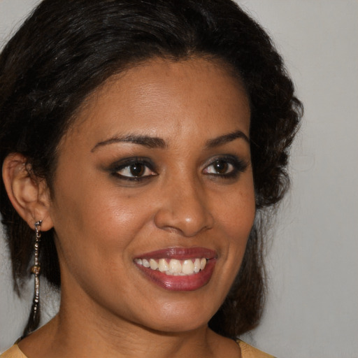 Joyful black young-adult female with long  brown hair and brown eyes
