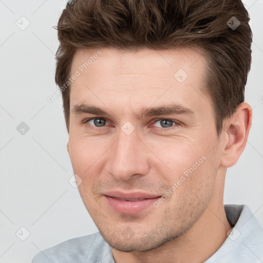 Joyful white young-adult male with short  brown hair and grey eyes