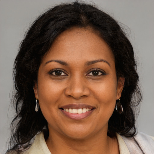 Joyful black young-adult female with long  brown hair and brown eyes