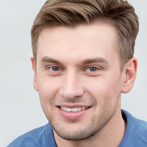 Joyful white young-adult male with short  brown hair and grey eyes