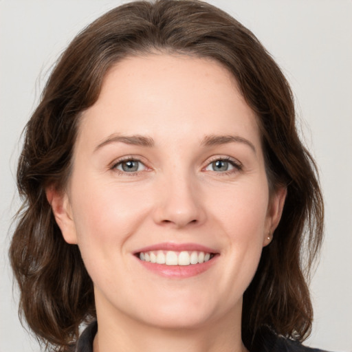 Joyful white young-adult female with medium  brown hair and green eyes