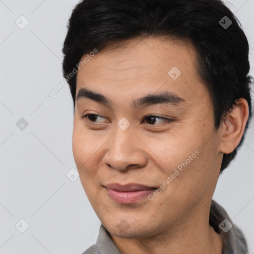 Joyful asian young-adult male with short  brown hair and brown eyes