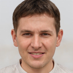 Joyful white young-adult male with short  brown hair and grey eyes