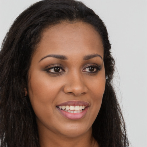 Joyful black young-adult female with long  brown hair and brown eyes
