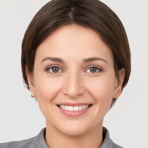 Joyful white young-adult female with short  brown hair and grey eyes