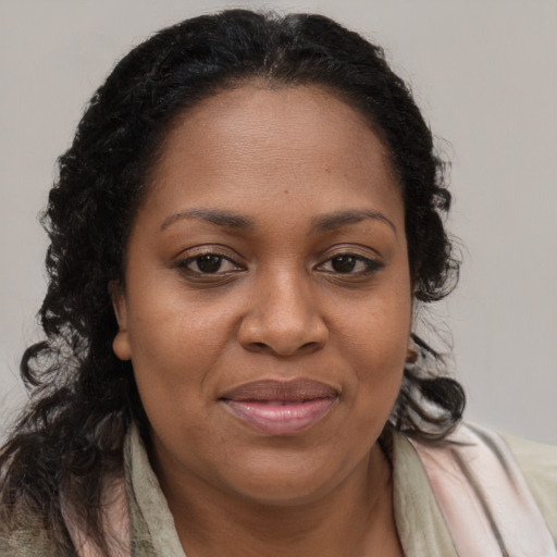 Joyful black young-adult female with long  brown hair and brown eyes