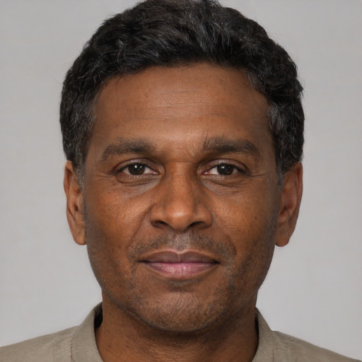 Joyful black adult male with short  black hair and brown eyes