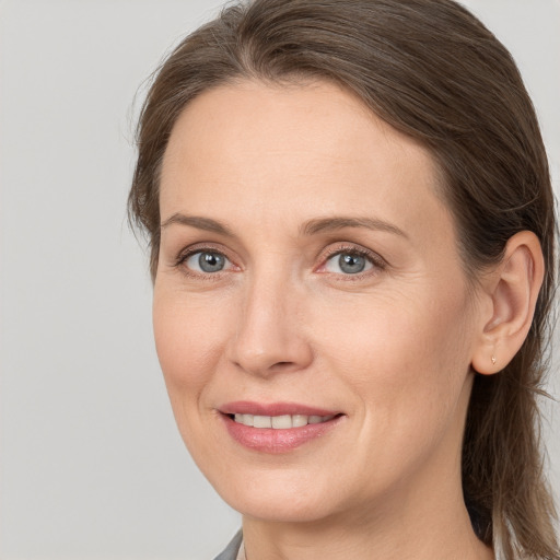 Joyful white adult female with long  brown hair and grey eyes