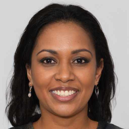 Joyful black young-adult female with long  brown hair and brown eyes
