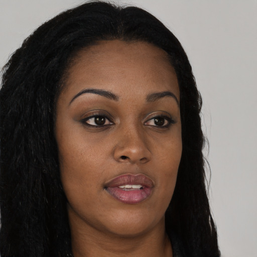 Joyful black young-adult female with long  brown hair and brown eyes