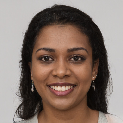 Joyful black young-adult female with long  black hair and brown eyes