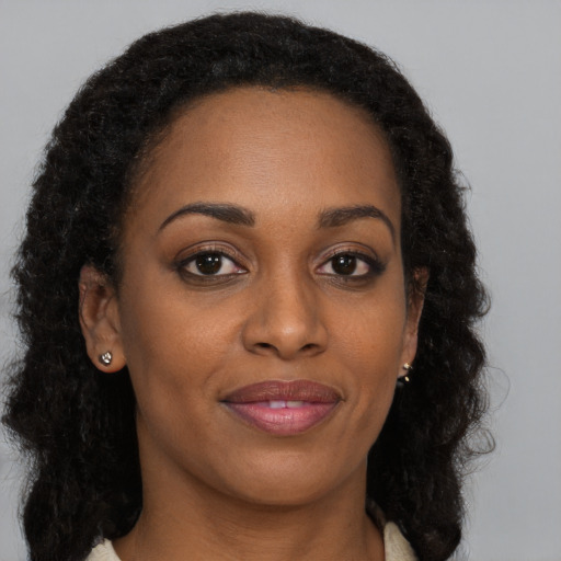 Joyful black young-adult female with long  brown hair and brown eyes