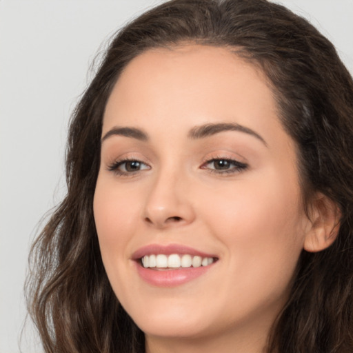 Joyful white young-adult female with long  brown hair and brown eyes