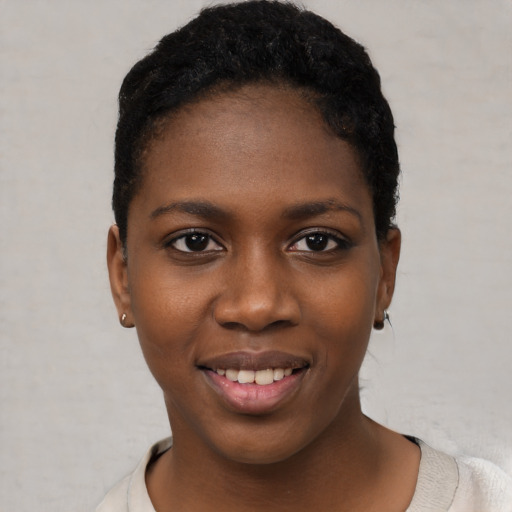 Joyful black young-adult female with short  black hair and brown eyes