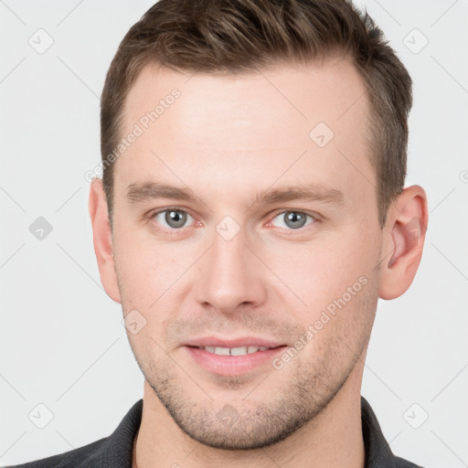 Joyful white young-adult male with short  brown hair and grey eyes