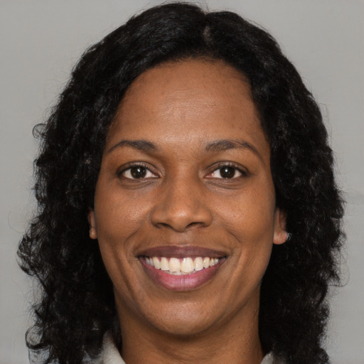 Joyful black adult female with long  black hair and brown eyes